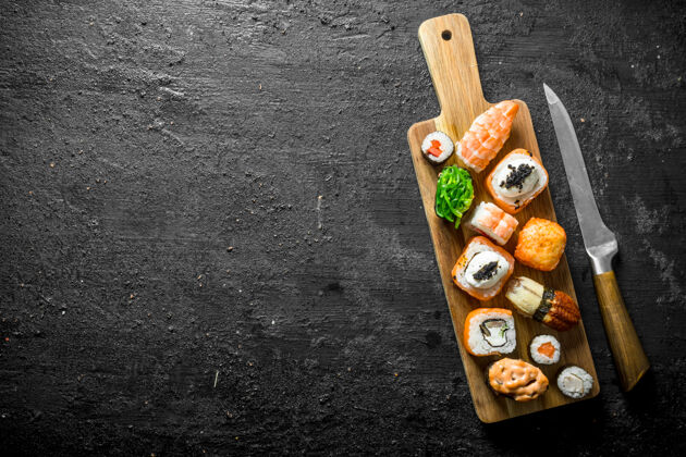 金枪鱼一套不同类型的寿司和卷放在木制的砧板上美味鱼寿司