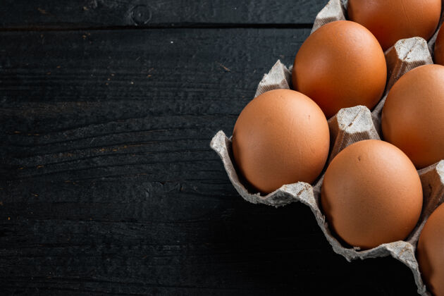 食品新鲜的鸡蛋放在纸蛋盒里 放在黑色的木桌上营养存储木表