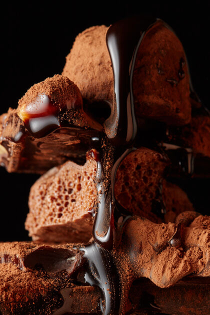 糖浆一块块巧克力和巧克力糖浆被隔离在一堵黑墙上可可部分裂纹
