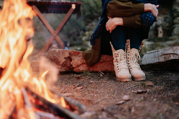 腿在一次冬季野餐中 坐在火炉旁的一个无法辨认的女人的腿乐趣木堆晚餐