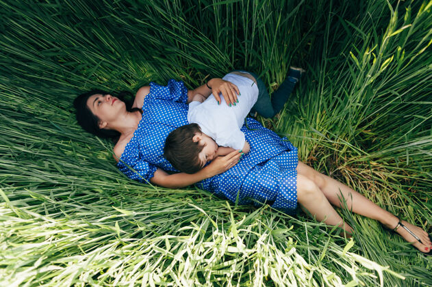 草地斯泰利的母亲和英俊的儿子在大自然中嬉戏妈妈一起休息