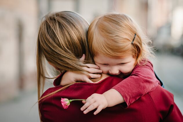 回来幸福家庭：妈妈抱着女儿捧着花束一起享受时光 站在欧罗巴国的街市上人在一起孩子