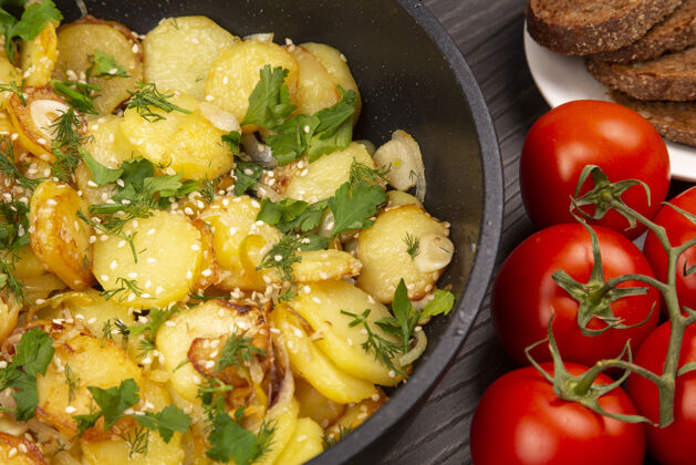 烤在木桌上的黑平底锅里用香草 香料和蔬菜煮土豆薯条餐桌健康