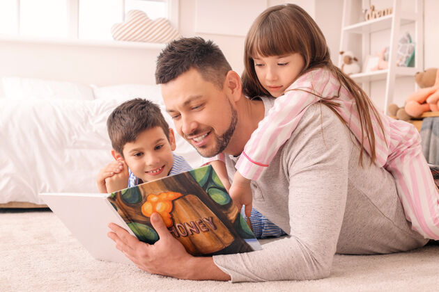舒适爸爸和他的小孩在家里读睡前故事男人姐妹故事