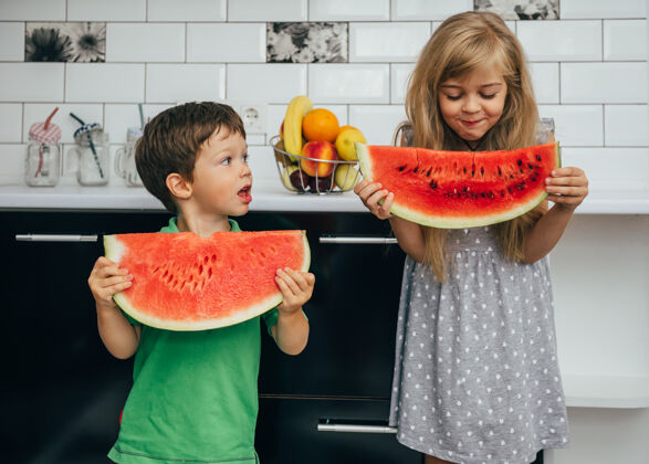 切片三个快乐微笑的孩子在厨房里吃西瓜食物美味快乐