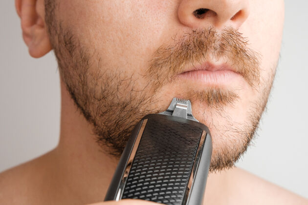 头发用电动剃须刀刮胡子或用有复印空间的修剪器脸健康男