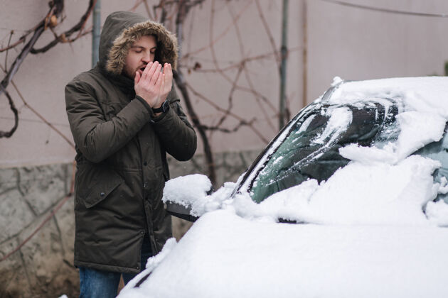 结冰帅哥用刷子把车从雪里擦干净手冬天户外运输汽车人