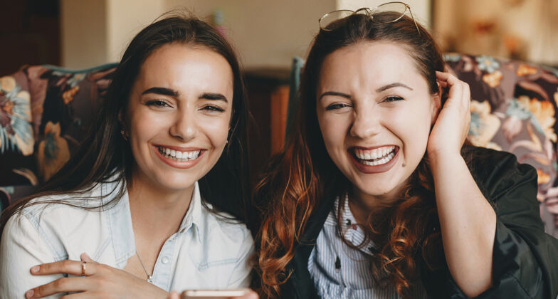 红发两位年轻漂亮的女朋友在咖啡店上完课后一边喝咖啡一边笑的特写照片咖啡屋情感化妆