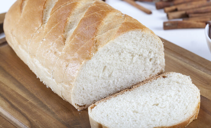 面包店在一张白色的餐桌上放着带香料的切片白面包活动面包互动