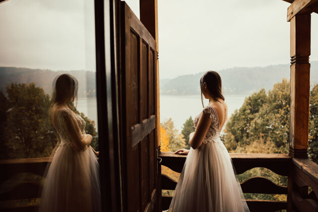 山穿着温柔婚纱的新娘站在阳台上看湖水蜜月阳台礼服