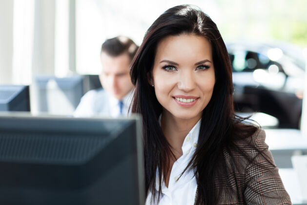员工在办公室工作的年轻女子 坐在办公桌旁 用笔记本电脑工人微笑女性