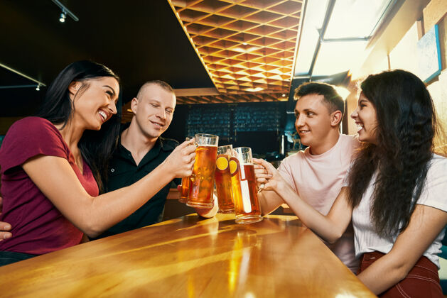 啤酒愉快的公司坐在一起 在酒吧喝啤酒在周末的侧视图品脱酒吧假期