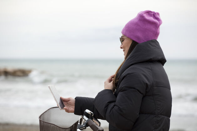 度假优雅的女人 骑着自行车 用着自行车手机近大海 文字的空间天空海洋女人