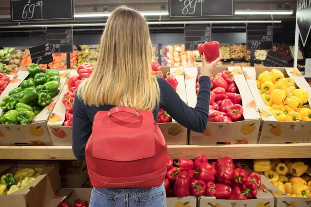 蔬菜一个女人站在杂货店的一排农产品前 手里拿着胡椒粉 在超市购物女人购物者胡椒