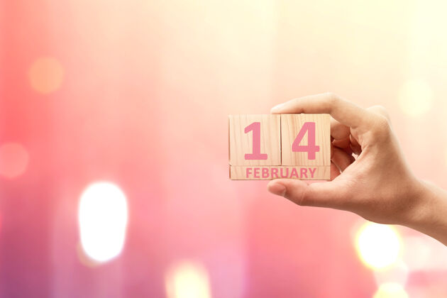 信息手持木制立方体的人手 上面有2月14日的标志 上面有彩色的墙情人节礼物天哪情人节日子情人节