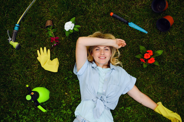 手套年轻女子躺在草地上 在花园里的园艺工具 顶部视图.女性园丁照顾植物户外 园艺爱好 花店的生活方式和休闲喷雾农场爱好