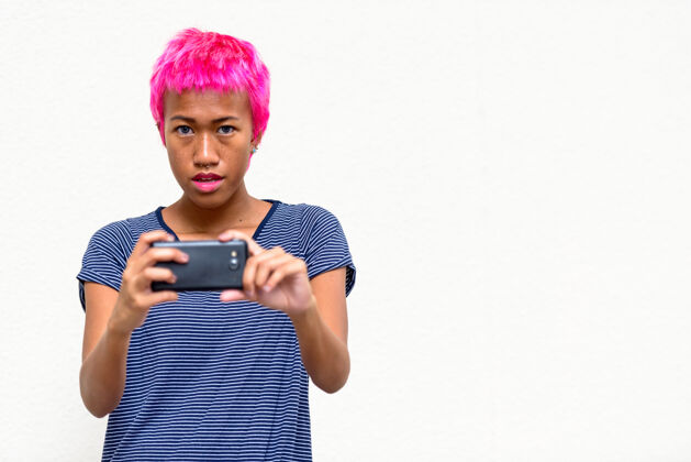短裤年轻叛逆的亚洲女人的肖像 粉色的头发映衬着白色的空间通信叛逆影响者