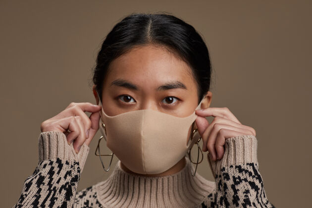 健康与美容戴着防护面具的亚洲女人的特写镜头 看着隔离在灰色墙上的正面流行疾病长相
