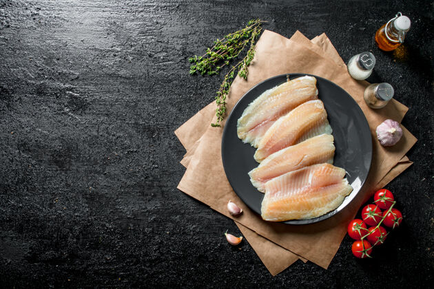 新鲜把罗非鱼鱼片放在盘子里 用纸 香料 百里香和西红柿鱼片鱼片切片