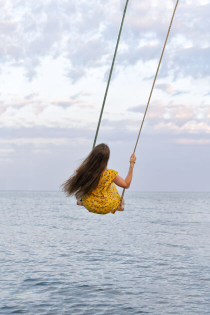岛屿长头发的女孩正在秋千上荡秋千水垂直框架长海洋热带