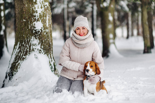 户外冬天带着狗散步的女人森林女主人在雪林里玩狗游戏冬天雪森林