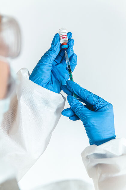注射穿防护服的医生或护士拿着注射器和疫苗免疫药品小瓶