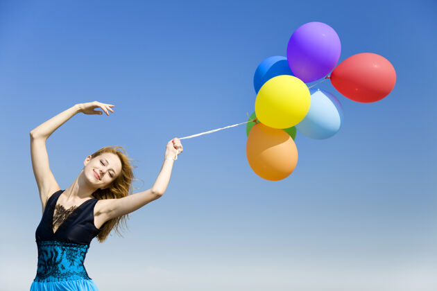自由红发女孩带着彩色气球在蓝天上气球天空黄色