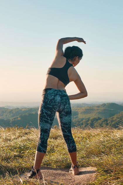 伸展一个女人穿着运动服装 伸展身体健康和积极的生活方式的形象身体能量女人