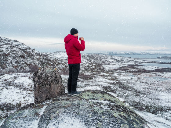 水平一个男人手里拿着一杯热茶 放在一只北极熊上山雪-覆盖北部山太好了极地的风景画旅行的概念北极徒步旅行童话