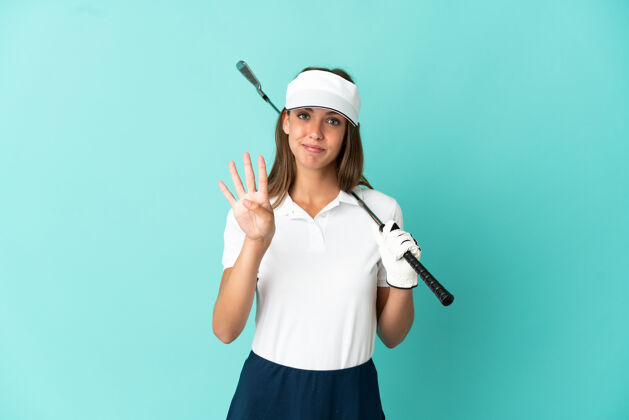 四在孤立的蓝色背景上打高尔夫球的女人快乐地用手指数着四个点女孩四