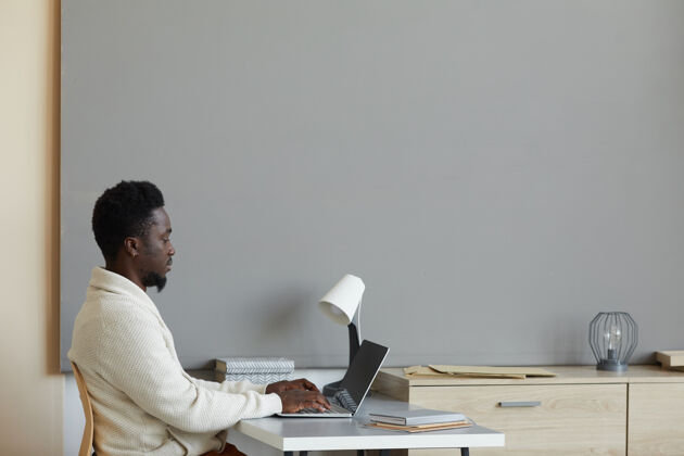 使用笔记本电脑坐在办公室里用笔记本电脑上网的非洲年轻人职业办公室人员