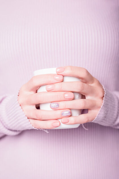 指甲女性手拿白色杯子 用粉色指甲油修指甲护理苍白杯子