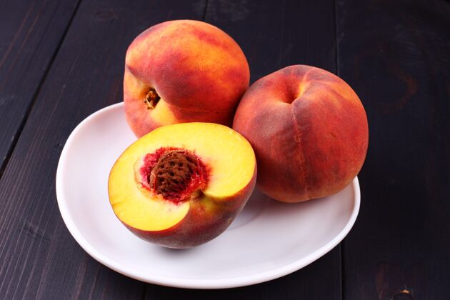 切的把桃子放在一个盘子里 放在一个深色的木头表面上桃子素食新鲜