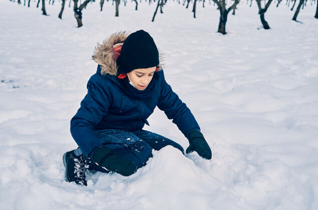 天气一个穿着暖和的高加索男孩戴着帽子玩雪冬天风景季节