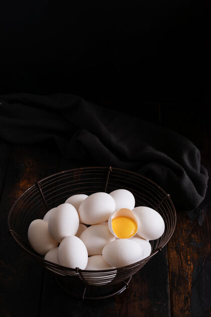 工厂白色生鸡蛋放在一个老式篮子里 放在黑暗的表面上使用鸡蛋早餐