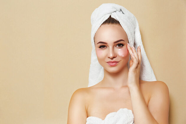 女性一个穿着白毛巾 脸上有补丁的女人摆姿势美容自我护理皮肤