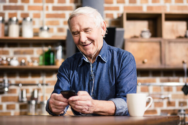 休闲快乐的老人拿着他的智能手机在家休息积极移动男性