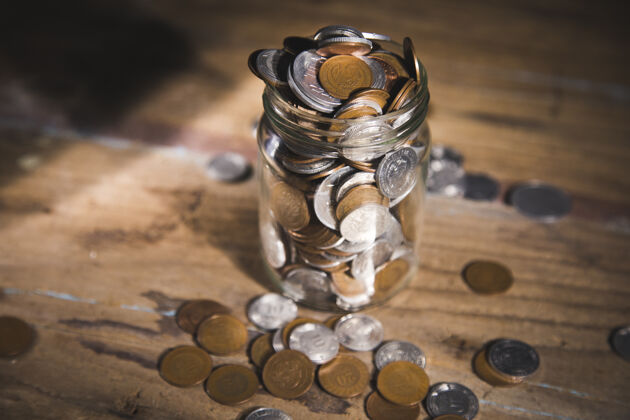 银行木桌上装满硬币的罐子老富有成功