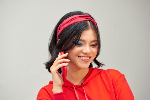 电话照片中的年轻快乐女士孤立地站在灰色背景下用手机交谈休闲亚洲女孩