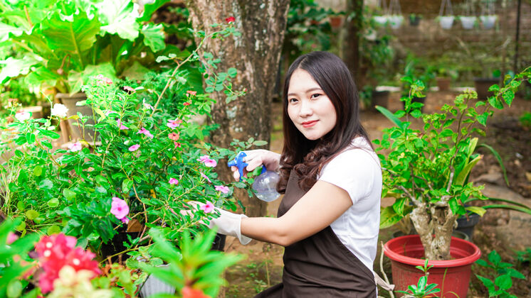 园艺亚洲女人在家花园浇花工具开花水