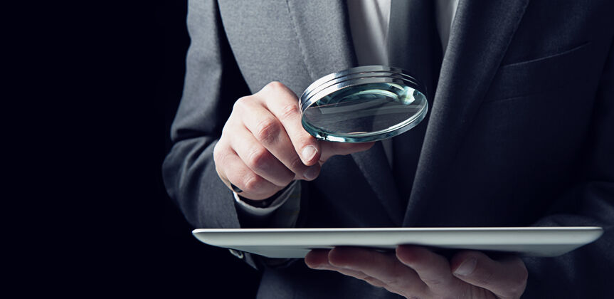 黑客商人用放大镜检查被感染的平板电脑互联网安全的概念技术登录间谍