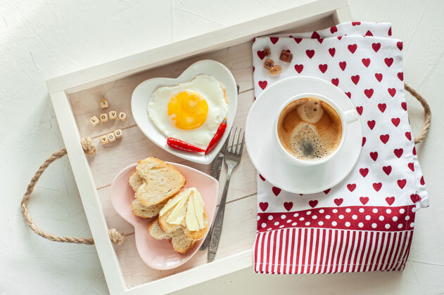 咖啡母亲节早餐托盘里有一杯咖啡 两盘炒蛋和心形面包 上面写着“我爱你妈妈”的字样 从上面看室内早晨托盘