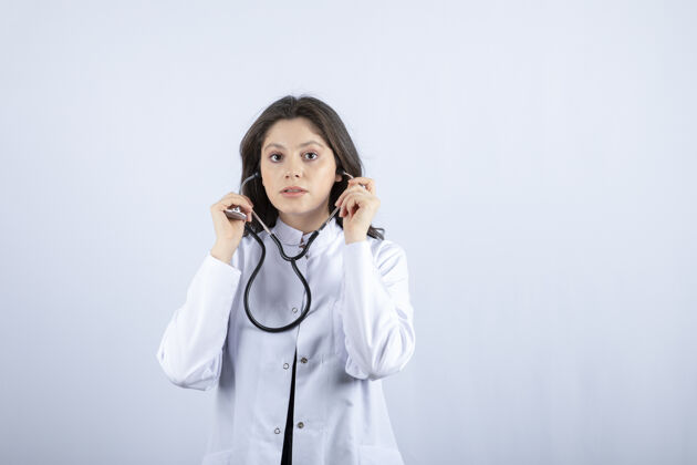 年轻人年轻女医生在白墙上用听诊器检查脉搏工作咨询治疗