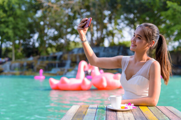 杯年轻美丽的亚洲女游客在湖边户外放松的画像成人肖像马尾辫