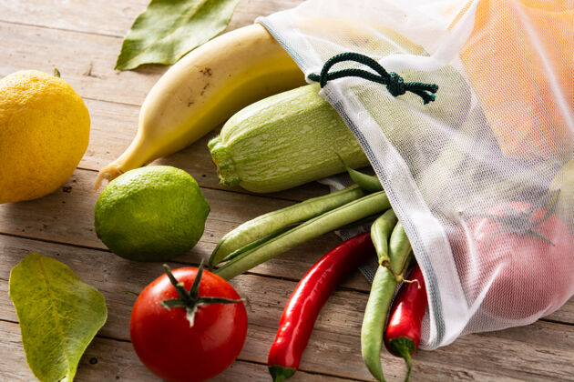 南瓜环保的可重复使用的购物袋与蔬菜和水果在木桌上蔬菜水果有机