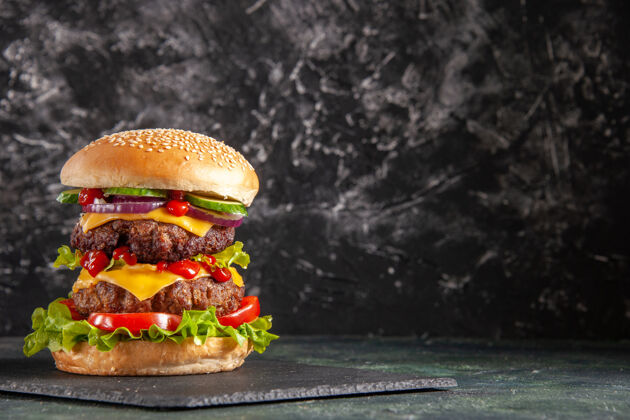 芝士汉堡美味的肉三明治和西红柿绿色的深色托盘在右边的黑色表面汉堡包晚餐面包