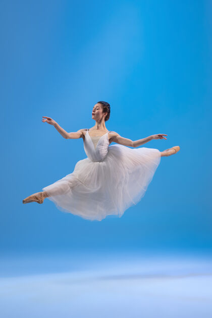 成功年轻优雅的白裙芭蕾舞演员 孤零零地站在蓝色的墙上模型运动手