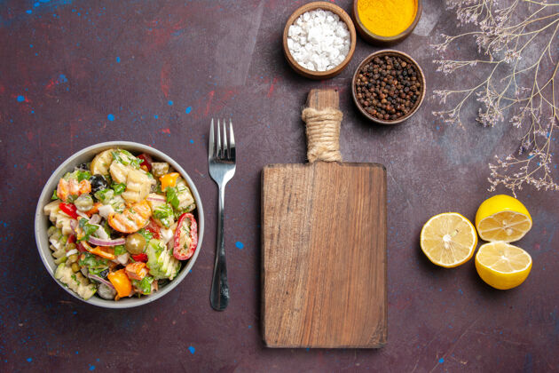 午餐俯瞰美味蔬菜沙拉与调味品和柠檬片对黑暗的桌子健康沙拉餐饮食切片菜肴晚餐