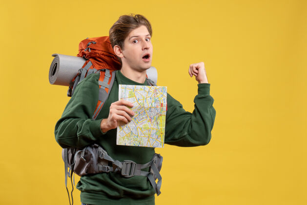 黄色正面图年轻男子背着背包拿着地图旅游年轻男性肖像