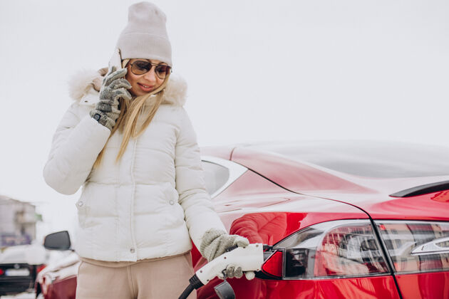 车辆女人充电红色电动车 在冬天的时候旅行者驾驶驾驶员